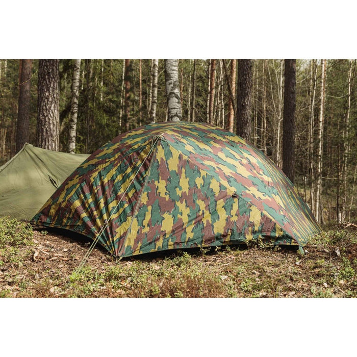 Tenda ripstop impermeabile per due persone militare belga allestita in una foresta con motivo mimetico e picchetti fissati.