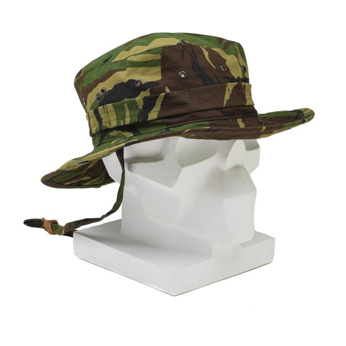 Cappello boonie militare olandese autentico con mimetica DPM, tesa larga, patta per il collo e sottogola regolabile sulla testa del manichino bianco.