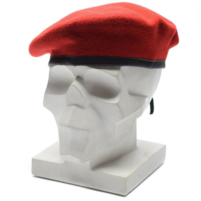 Berretto in vera lana rosso corallo dell'esercito tedesco con cinturino in pelle regolabile esposto su una testa di manichino con teschio bianco.
