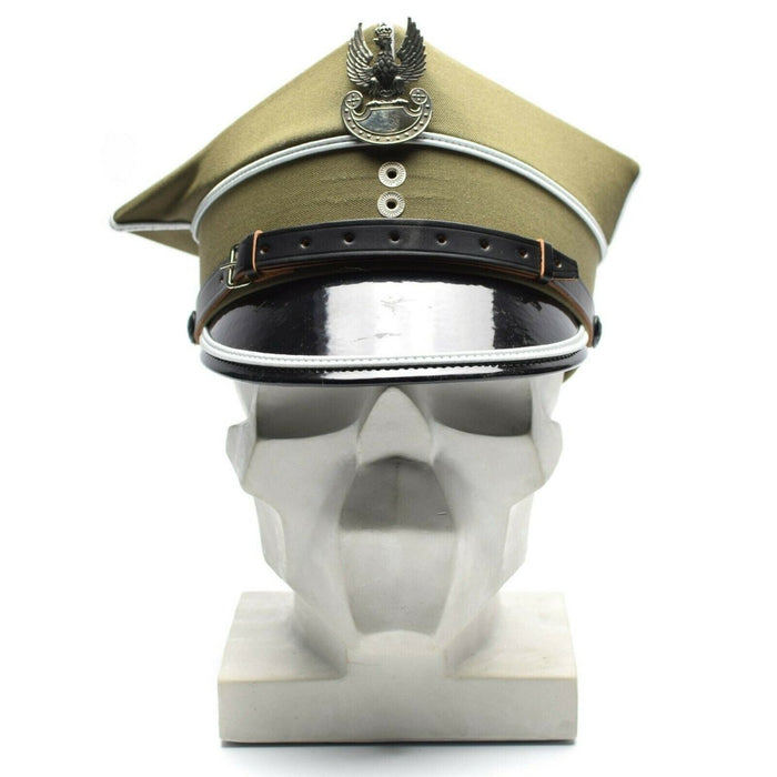 Berretto con visiera da ufficiale militare polacco autentico con coccarda d'aquila e visiera in pelle sulla testa di un manichino bianco.