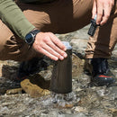 Person filling a Katadyn BeFree Tactical 1.0L water filter bottle from a stream during outdoor adventure.