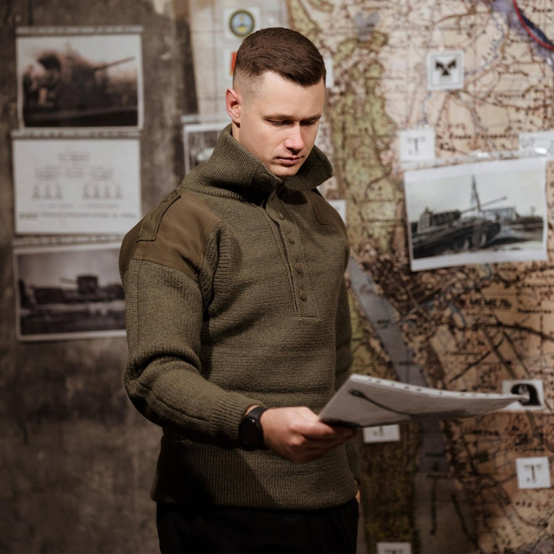 Man wearing olive wool Austrian Army Alpine Pullover sweater reading a map in a vintage military setting