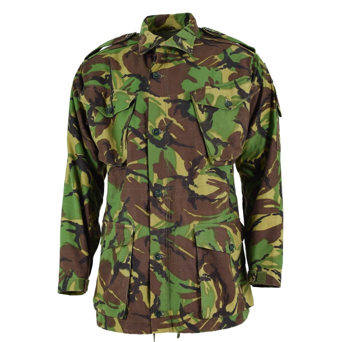 Giacca grembiule da combattimento BDU dell'esercito britannico in mimetica boschiva con tasche multiple e vestibilità regolabile per l'uso nella stagione fredda.