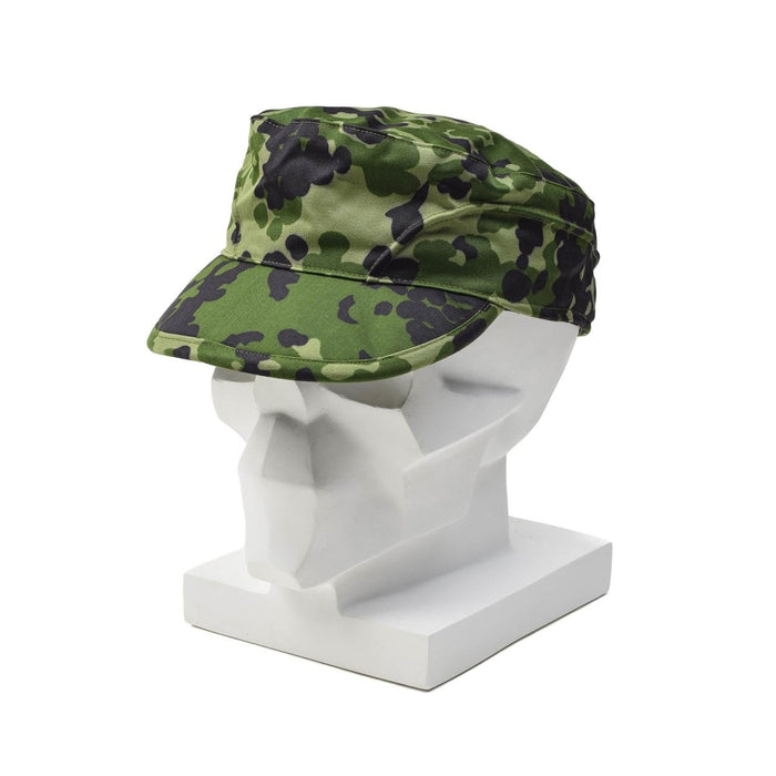 Berretto da campo mimetico originale militare danese M84 con paraorecchie pieghevoli mostrato su una testa di manichino bianco.