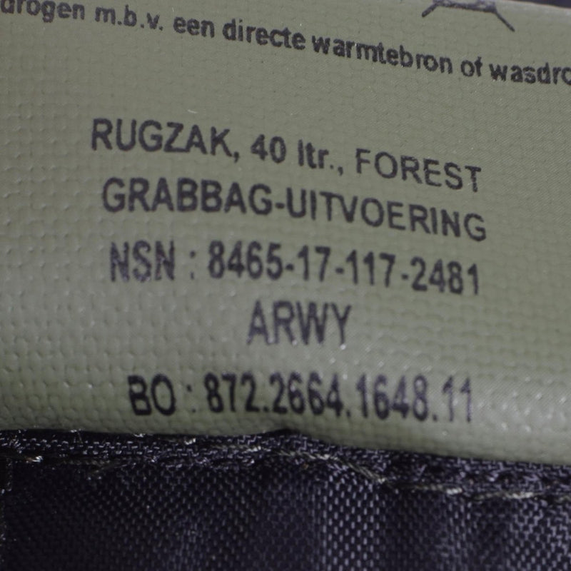Close-up of Dutch military woodland camo daypack label showing 40-liter capacity and NSN number on textured fabric.