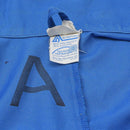 Close-up of blue Oko-Tex coverall fabric label showing 65% polyester and 35% cotton composition with sewn seam details.