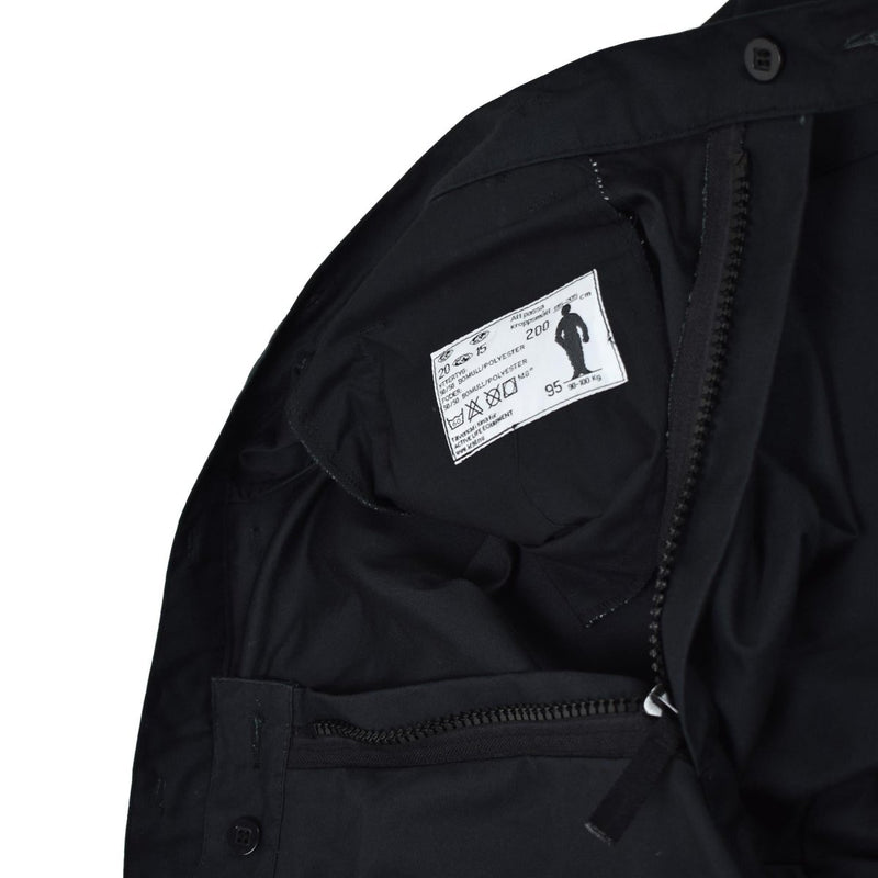 Close-up of inside black Swedish Army M90 thermal pants showing label, zipper, and button details.