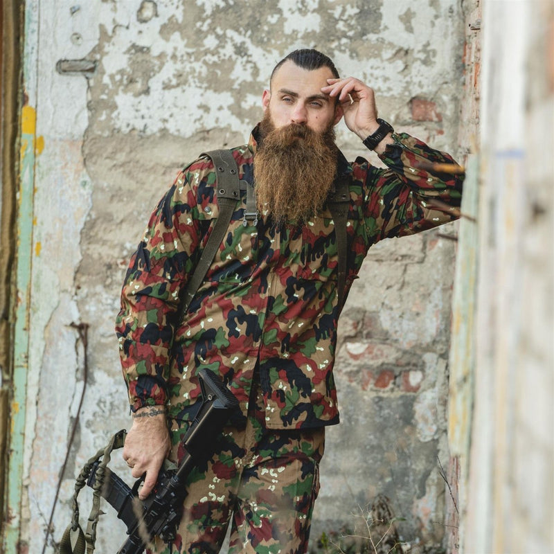 Man wearing Original Swiss Army M83 Alpenflage camo jacket with reinforced elbows and chest pockets outdoors