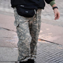 Person wearing original U.S. Military field pants in digital tiger stripe camo with cargo pockets walking outdoors