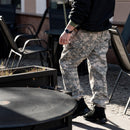 Man wearing original U.S. Military digital tiger stripe camo pants standing outdoors near chairs and tables
