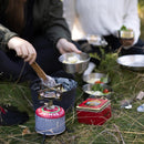 Primus ClassicTrail Stove 130 wide flame camping burner in use outdoors with cooking utensils and ingredients nearby.