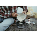 Person pouring batter from 1.3L pot into pan on Primus Essential Stove Set outdoors during camping trip
