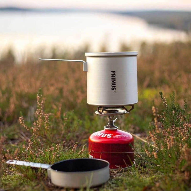 Primus Essential Trail KIT lightweight camping stove set with 1L pot cooking outdoors on grass background