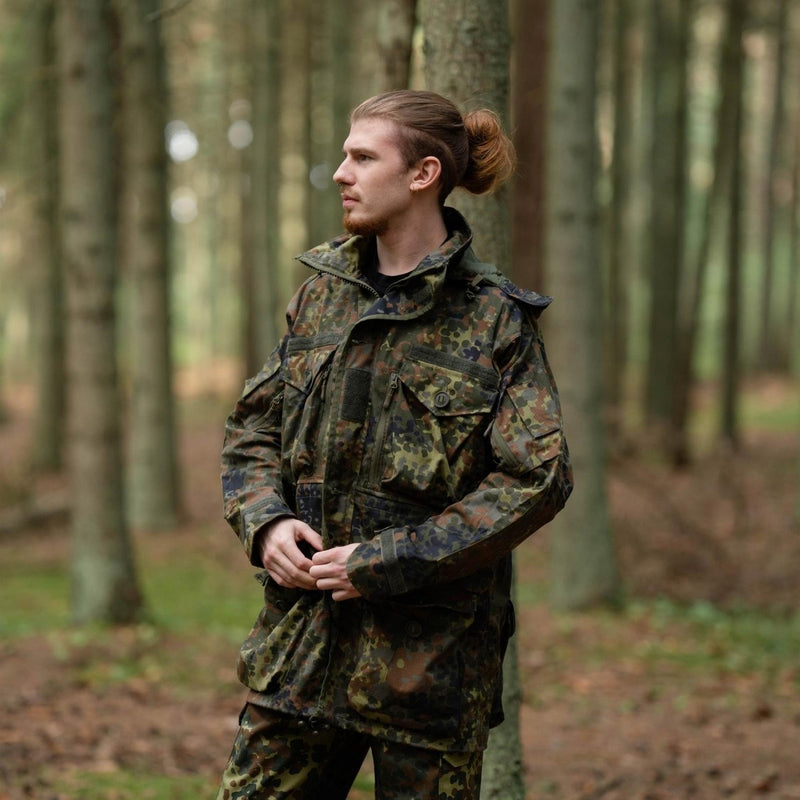 Man wearing TACGEAR German military style Flecktarn smock jacket with YKK zipper in a forest setting